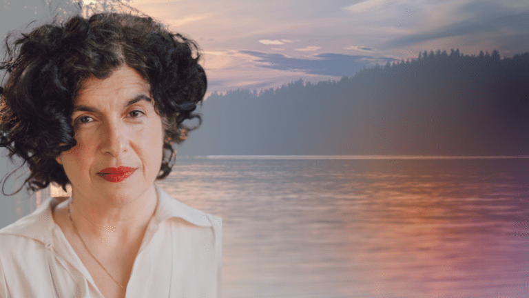 Alinah Azadeh image description: Alinah, a middle-aged, Iranian woman with short dark curly hair, is in front of a peaceful water scene.