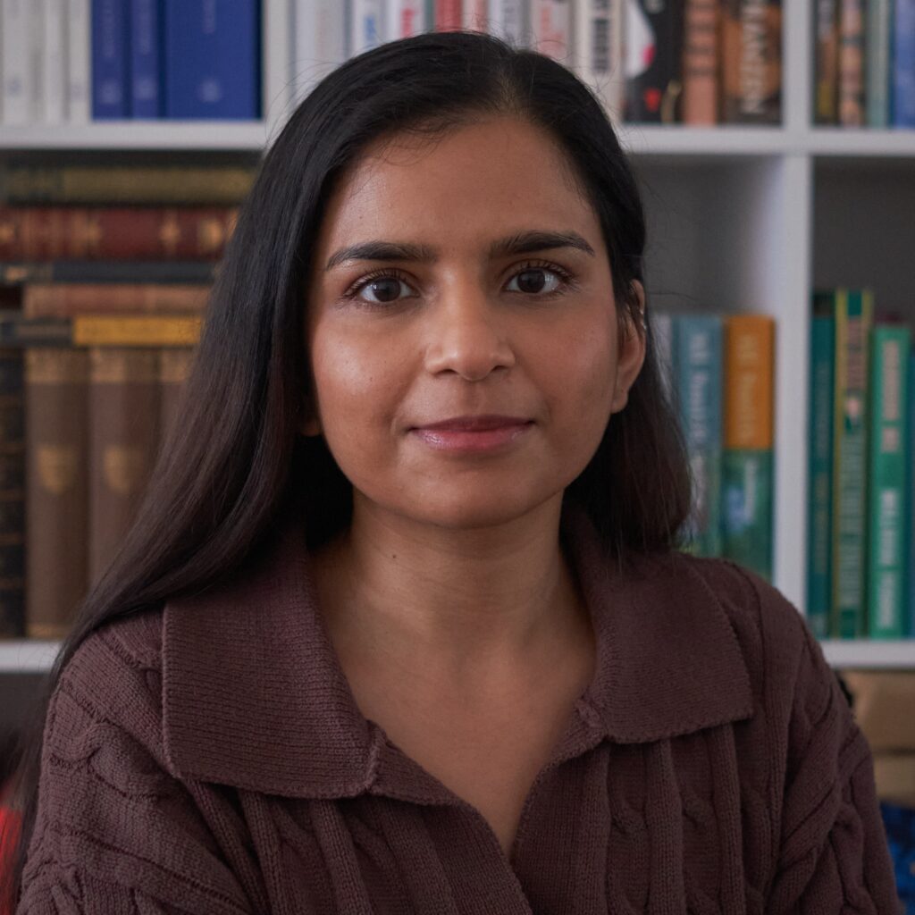 Areen Ali, a young Asian woman with long dark hair and a brown top and books behind
