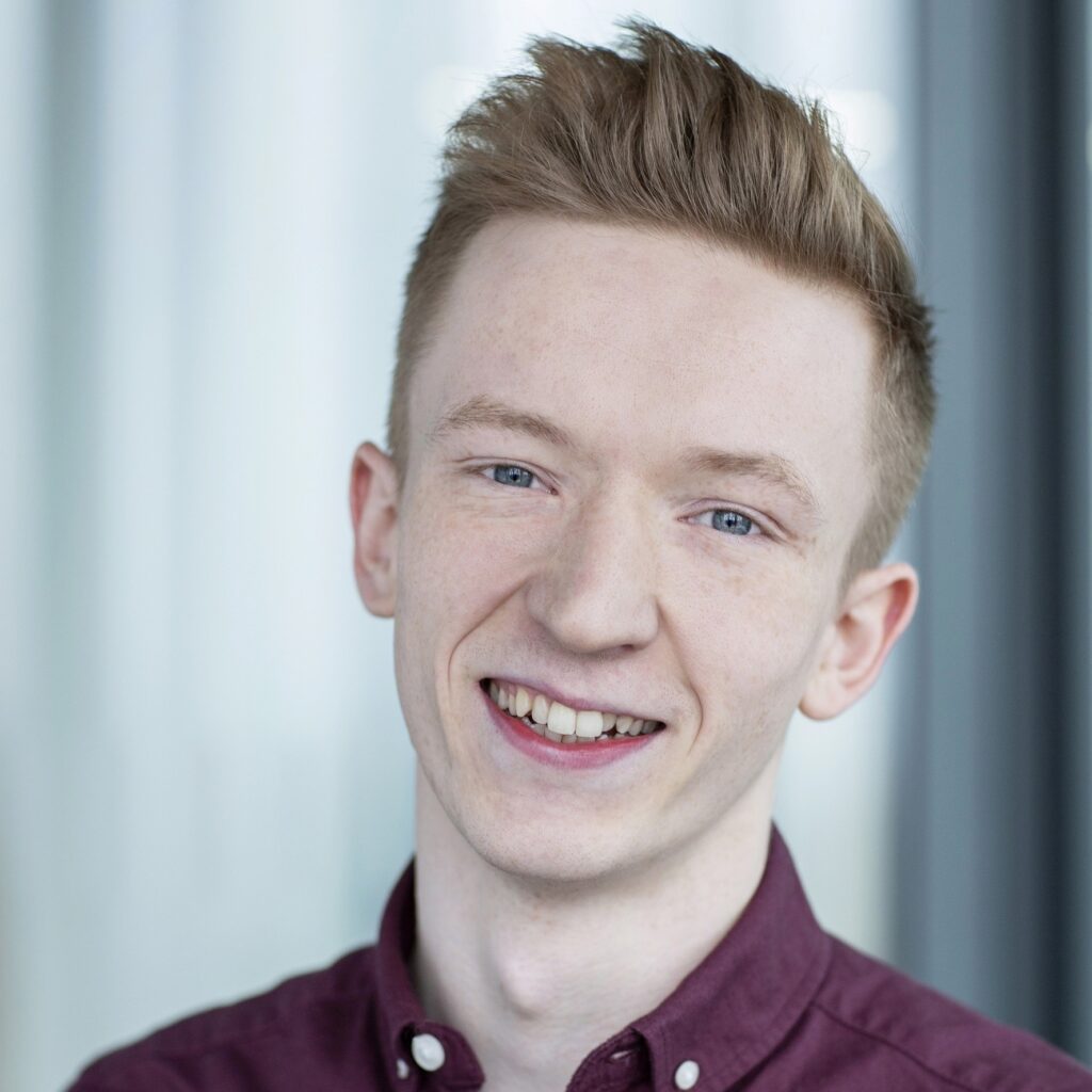 Joe Thomas, a young white man with ginger hair and a dark red shirt