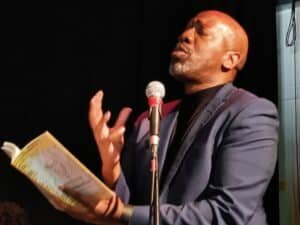 Roy McFarlane, a black, bald performance poet reads passionately