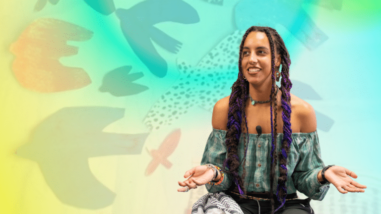 Erin James Erin is a young and black with long dark braids. They are sat in front of a collaged scene of birds.